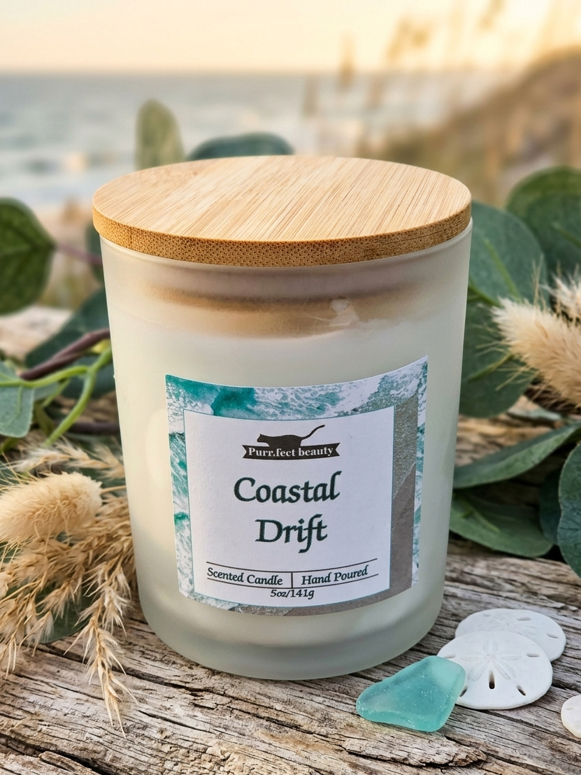 Candle labeled 'Coastal Drift' with a wooden lid on a wooden surface with natural elements.