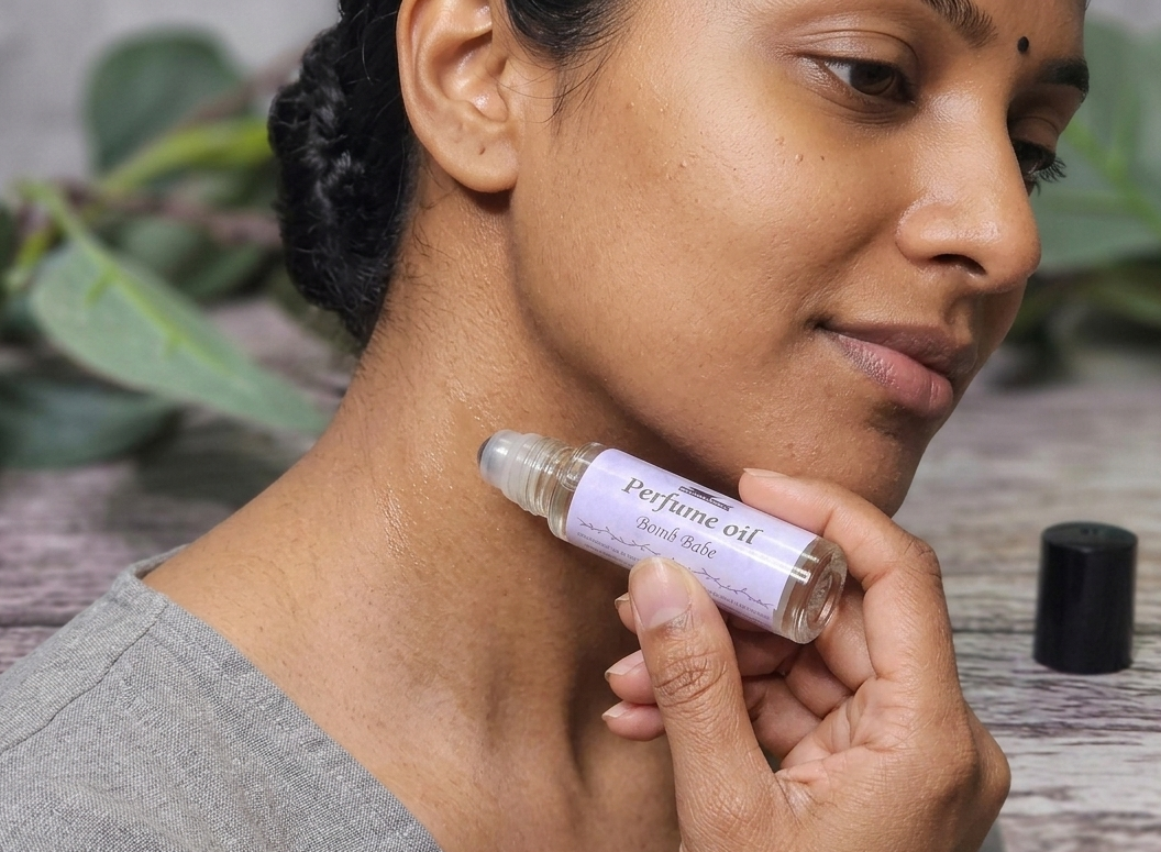 Person applying perfume oil to their neck with a natural background