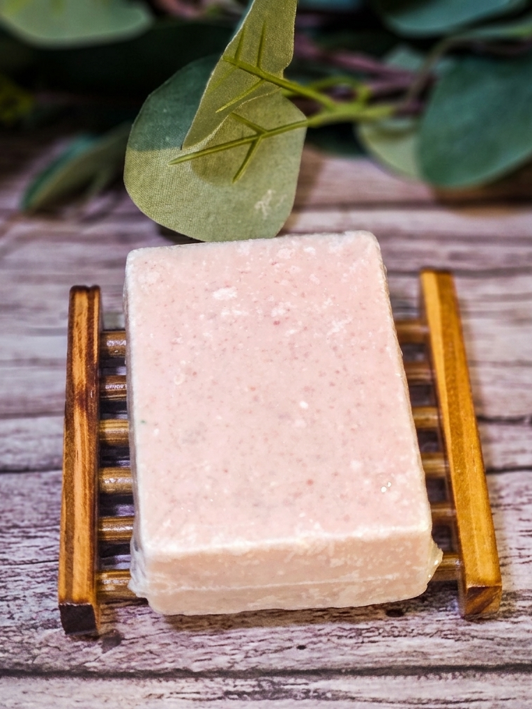Bar of soap on a wooden stand with green leaves in the background
