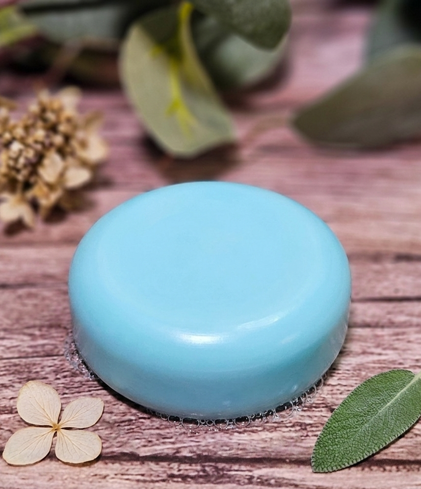 Blue round shampoo bar on a wooden surface with leaves and flowers