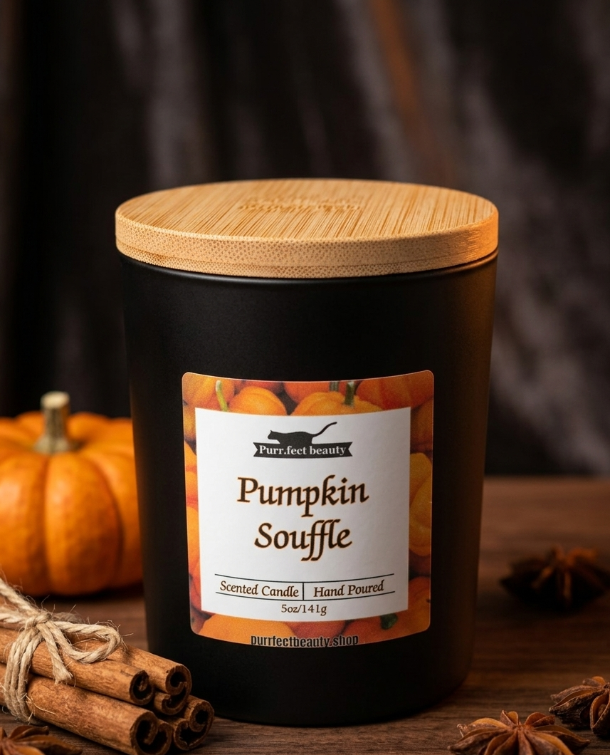 Black candle jar with wooden lid labeled 'Pumpkin Souffle' on a wooden surface with pumpkins and cinnamon sticks.