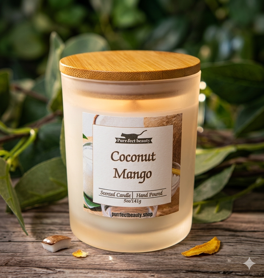 Coconut Mango scented candle with wooden lid on a wooden surface with green leaves in the background