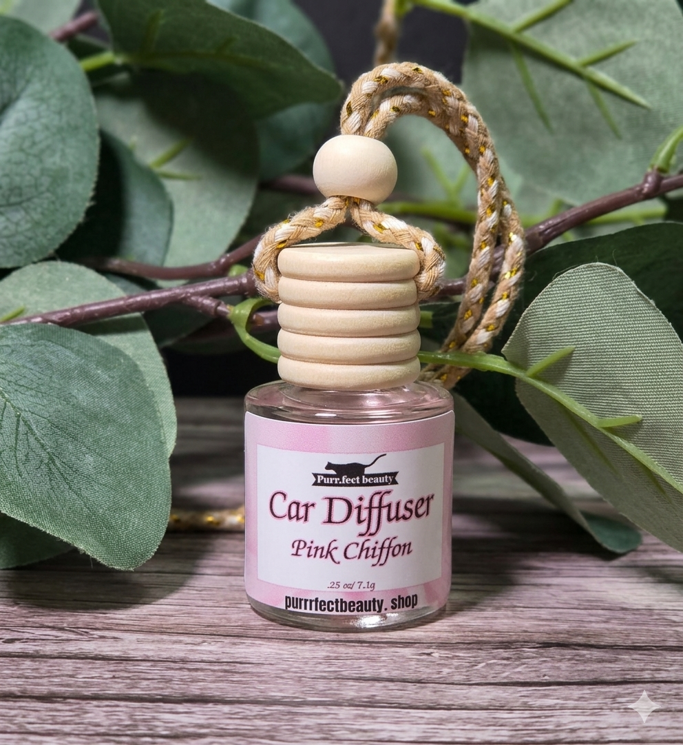 Pink Chiffon Car diffuser with pink label on a wooden surface with green leaves in the background