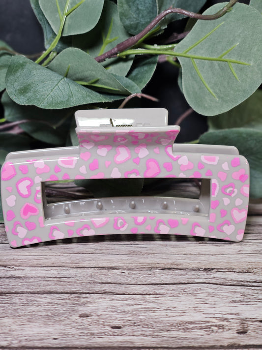 Hair clip with pink heart pattern on a wooden surface