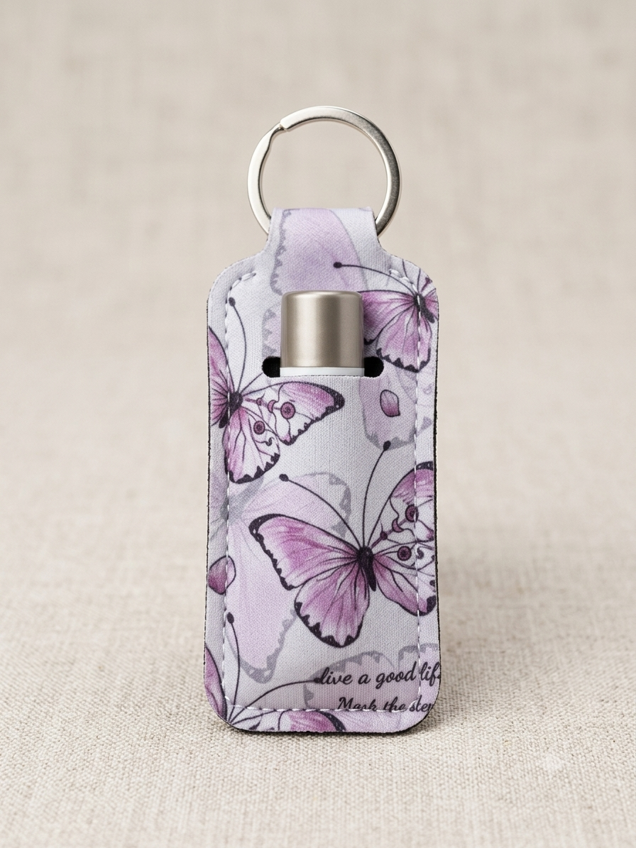 A rectangular leather keychain holder with a silver metal ring an, decorated with a purple and pink butterfly pattern on a light background, set against a neutral beige textured backdrop.