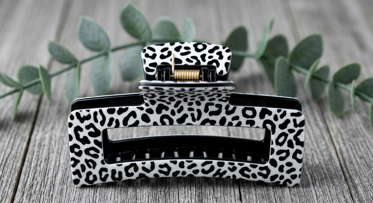 Leopard print hair clip on a wooden surface with green leaves