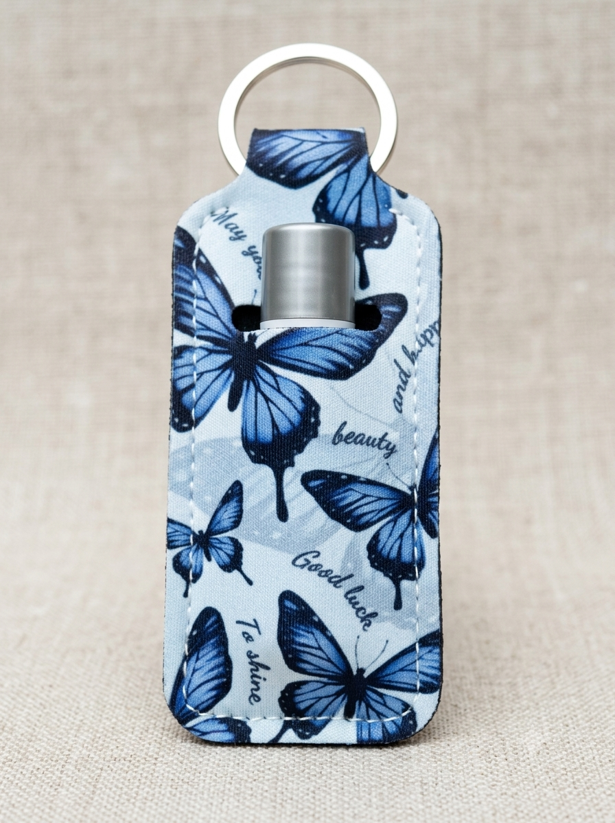 A small insulated bottle or tumbler wrapped in a light blue fabric sleeve printed with blue butterflies and black script words, shown with a silver metal ring on a beige textured background.
