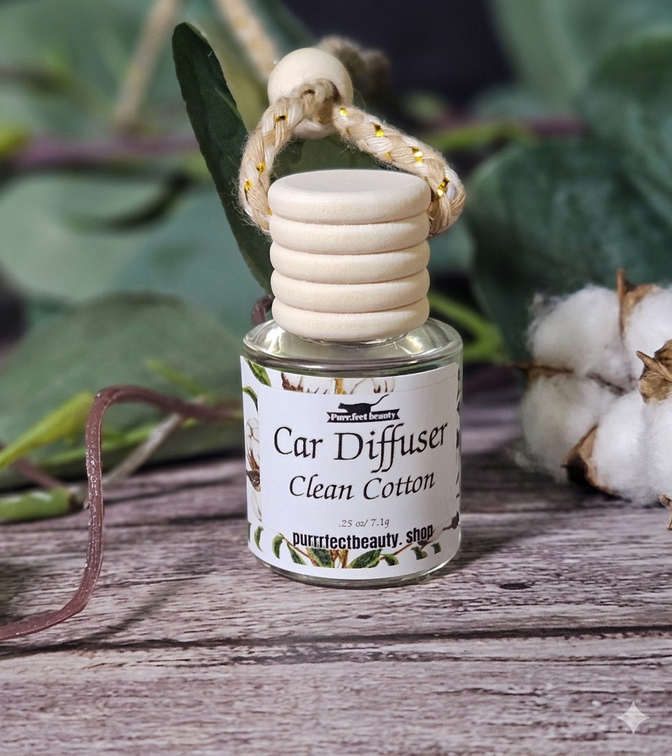 Car diffuser labeled 'Clean Cotton' on a wooden surface with plants in the background