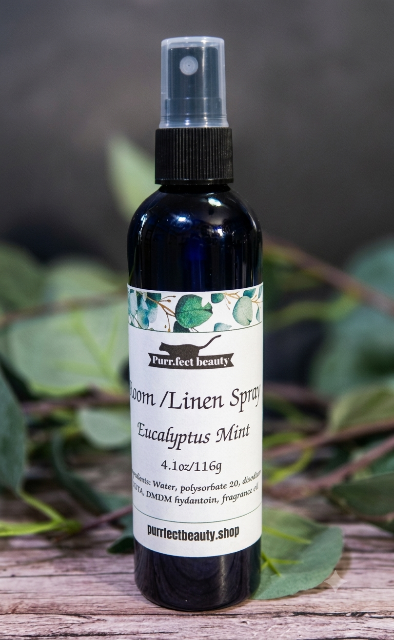 Room/Linen spray bottle with Eucalyptus Mint scent on a wooden surface with greenery in the background.
