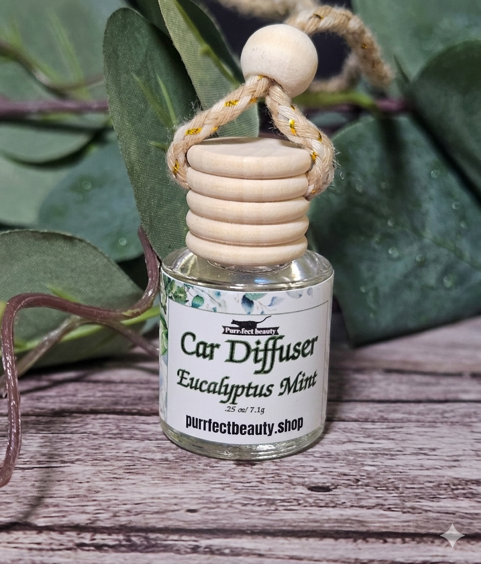 Eucalyptus Mint Car diffuser with wooden top on a wooden surface with green leaves in the background