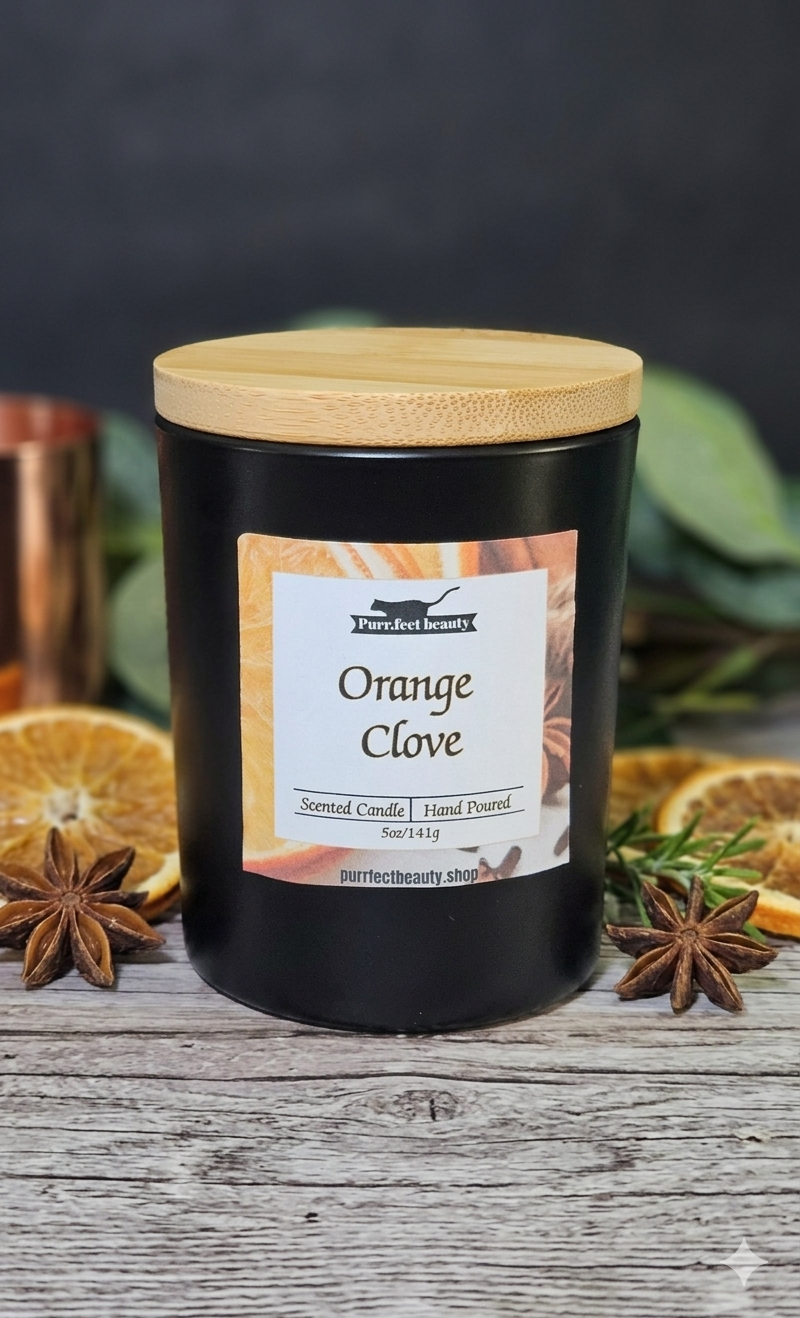 Black candle labeled 'Orange Clove' with a wooden lid on a rustic surface with dried oranges and star anise.